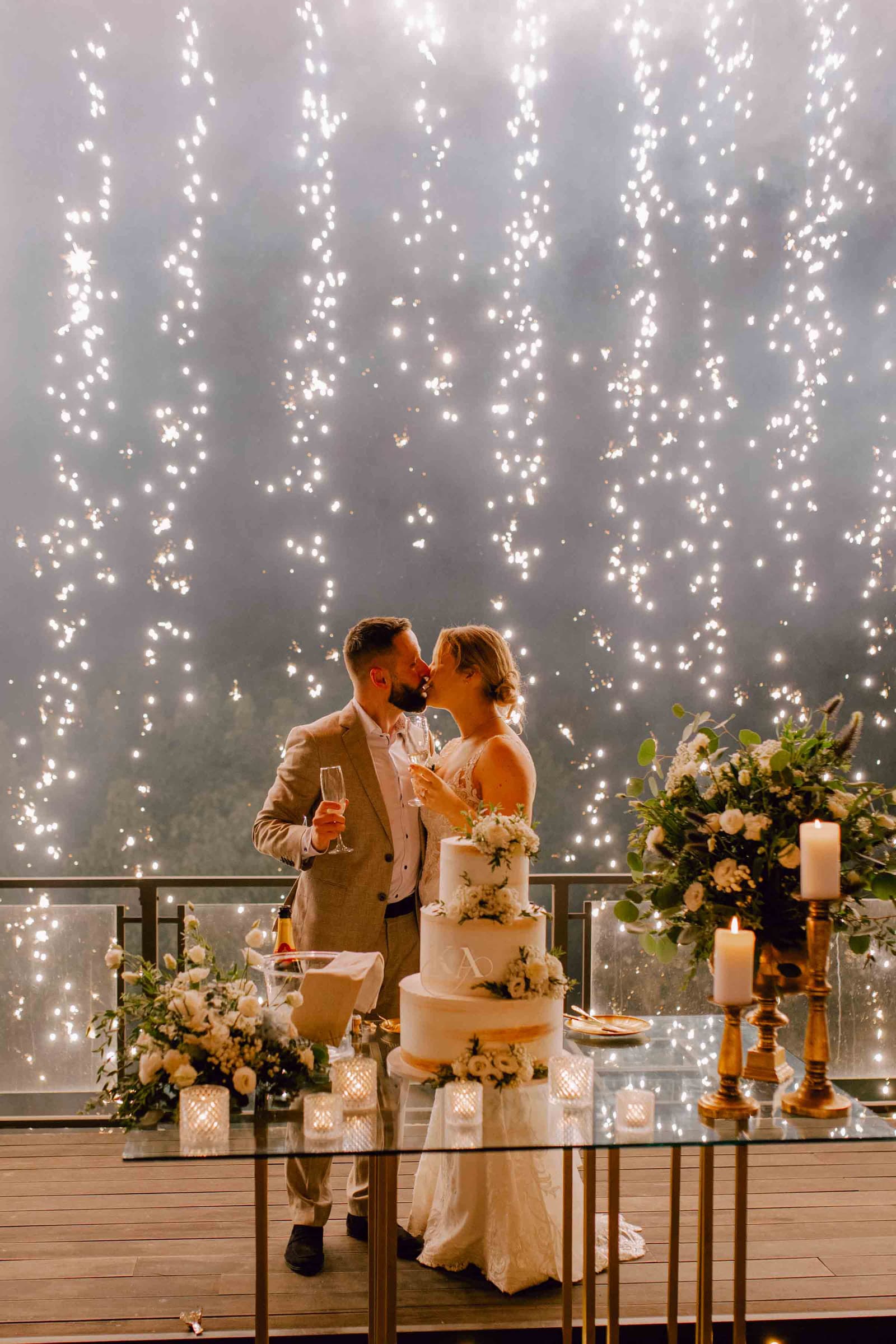 A couple beneath cascading sparkler fountains at a candlelit palace reception