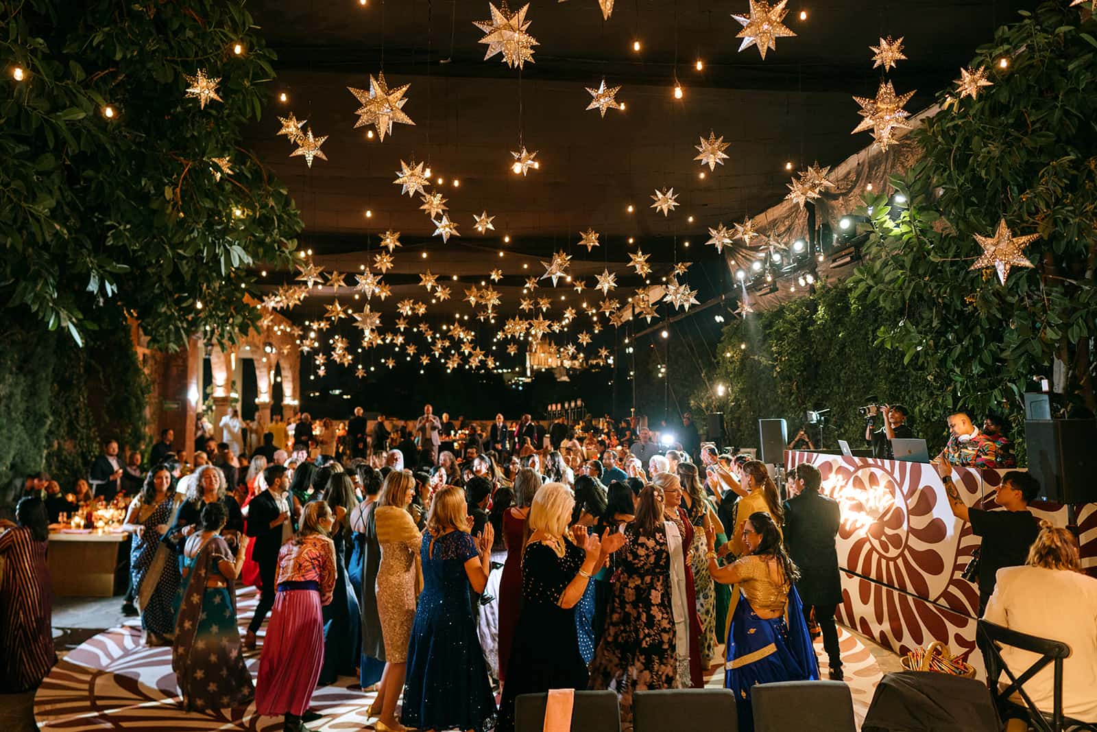 Guests dancing beneath glowing lanterns and string lights at a night celebration
