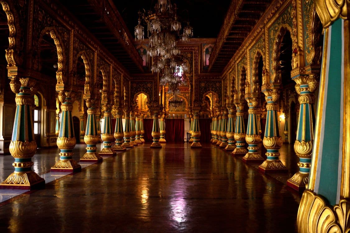 An opulent palace ballroom with carved gilded pillars and grand chandeliers